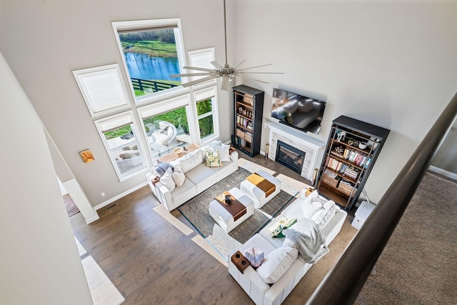 living room featuring ceiling fan, a towering ceiling, and dark hardwood / wood-style floors