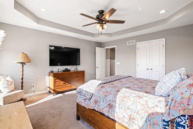 bedroom with carpet flooring, a closet, ceiling fan, and a tray ceiling