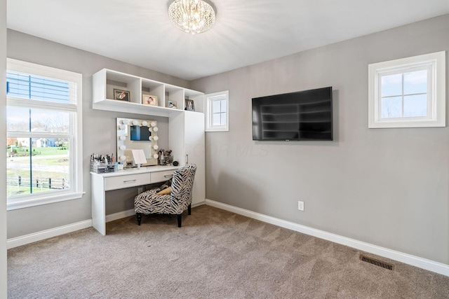 carpeted home office with a notable chandelier