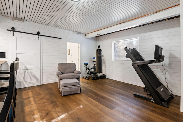 workout room with a barn door and dark hardwood / wood-style floors