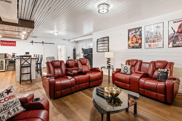 living room featuring wooden walls, a barn door, wood-type flooring, and wine cooler