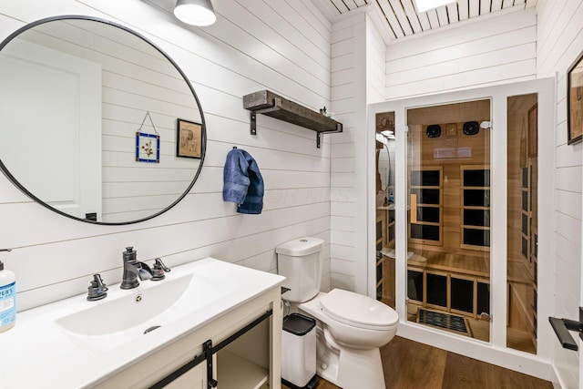 bathroom with vanity, hardwood / wood-style flooring, toilet, and wooden walls