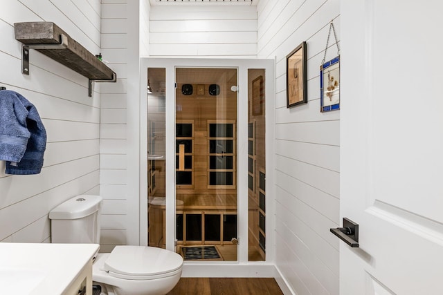 bathroom featuring hardwood / wood-style floors, vanity, toilet, and wood walls