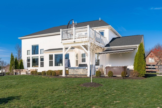 back of house featuring a yard, a balcony, and a hot tub