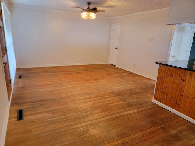 empty room with ceiling fan, light hardwood / wood-style flooring, and crown molding