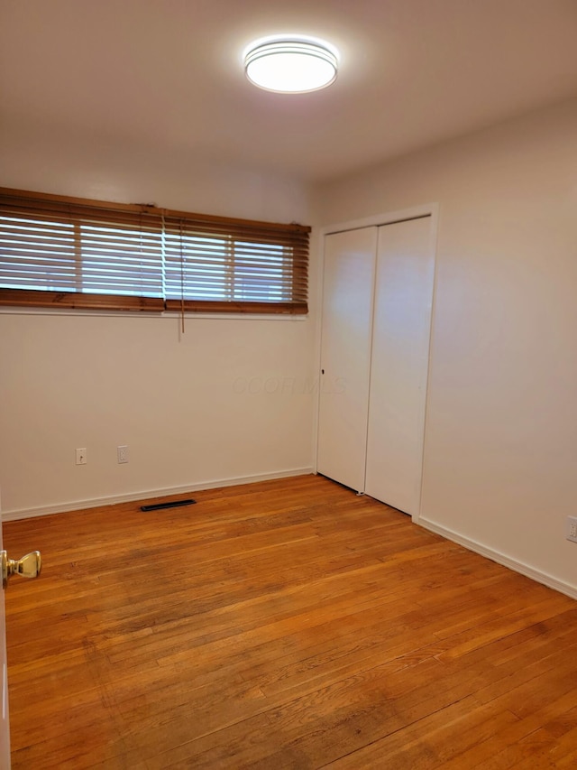 unfurnished bedroom with light wood-type flooring and a closet