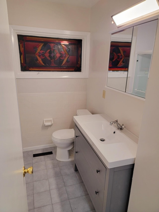 bathroom featuring tile patterned flooring, vanity, toilet, and tile walls