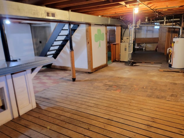 basement with hardwood / wood-style flooring and water heater