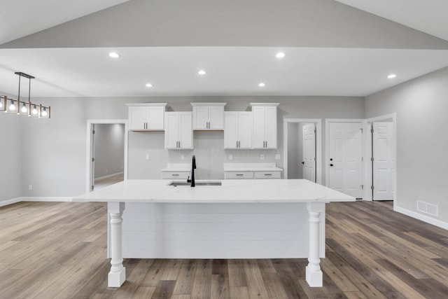 kitchen featuring a spacious island, sink, white cabinetry, light stone countertops, and lofted ceiling