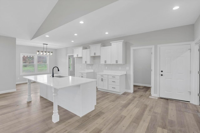 kitchen featuring sink, an island with sink, white cabinetry, and backsplash