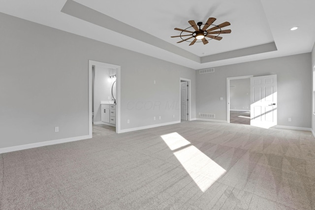 unfurnished room featuring ceiling fan, carpet flooring, and a tray ceiling