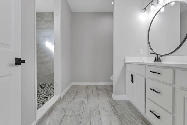 bathroom with a tile shower, toilet, and vanity