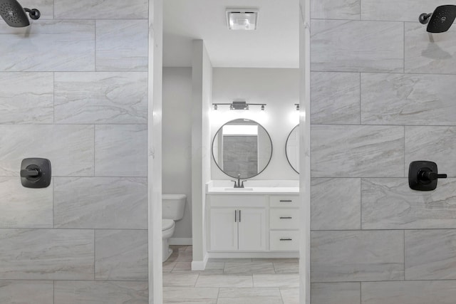 bathroom with a tile shower, toilet, and vanity