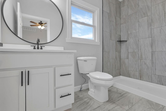 bathroom with ceiling fan, toilet, vanity, and tiled shower