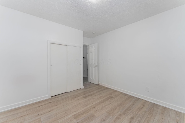 unfurnished bedroom featuring light wood-type flooring, a textured ceiling, and a closet