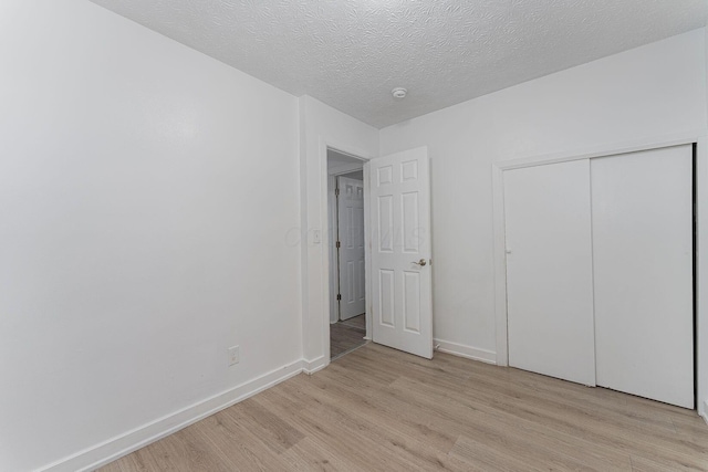 unfurnished bedroom featuring a textured ceiling, light hardwood / wood-style flooring, and a closet