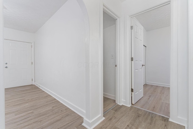 corridor featuring a textured ceiling and light hardwood / wood-style floors