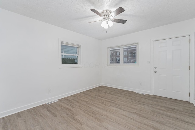 empty room featuring ceiling fan, a textured ceiling, and light hardwood / wood-style flooring