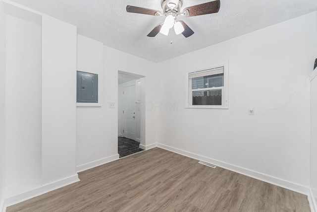 spare room with hardwood / wood-style floors, ceiling fan, a textured ceiling, and electric panel