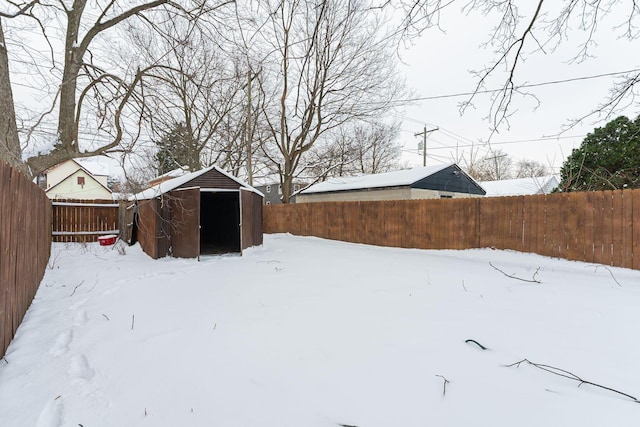 yard layered in snow featuring a storage unit