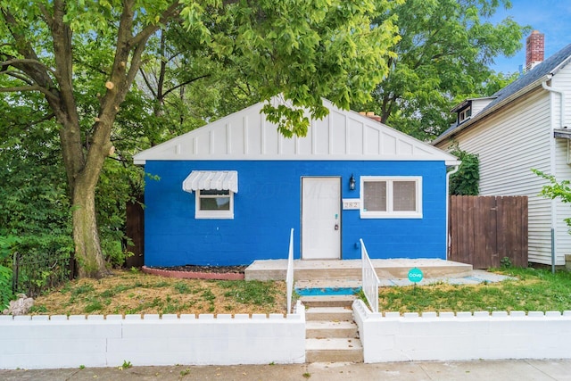 view of front of property with fence, concrete block siding, and board and batten siding