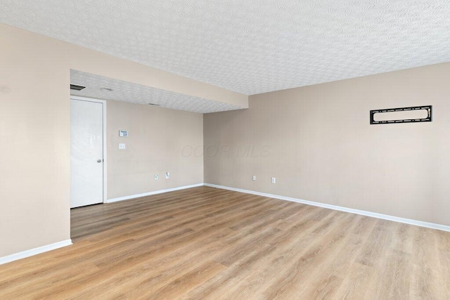 empty room with a textured ceiling and light hardwood / wood-style floors