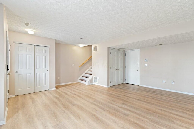 basement featuring light hardwood / wood-style flooring and a textured ceiling