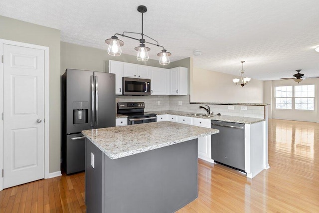 kitchen featuring backsplash, stainless steel appliances, decorative light fixtures, and white cabinets