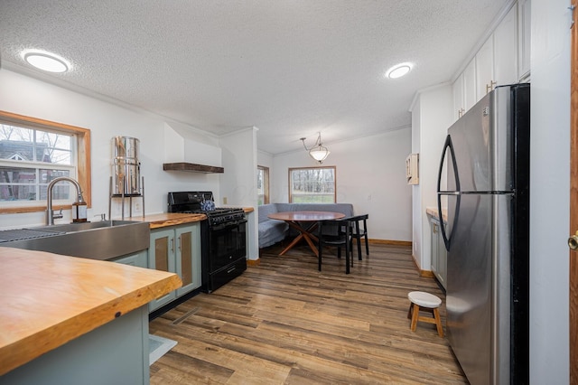 kitchen with wood counters, sink, dark hardwood / wood-style floors, stainless steel fridge, and black range with gas cooktop