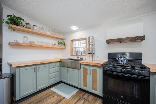 kitchen featuring wood counters, dark wood-type flooring, sink, ornamental molding, and black range with gas cooktop