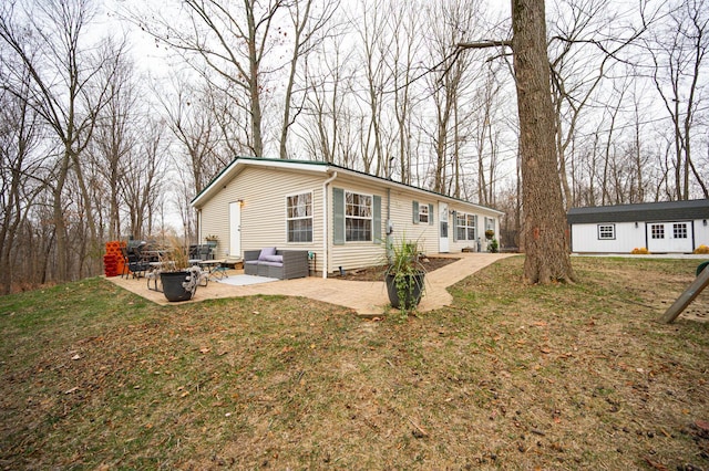 back of property with an outbuilding, a yard, an outdoor living space, and a patio area