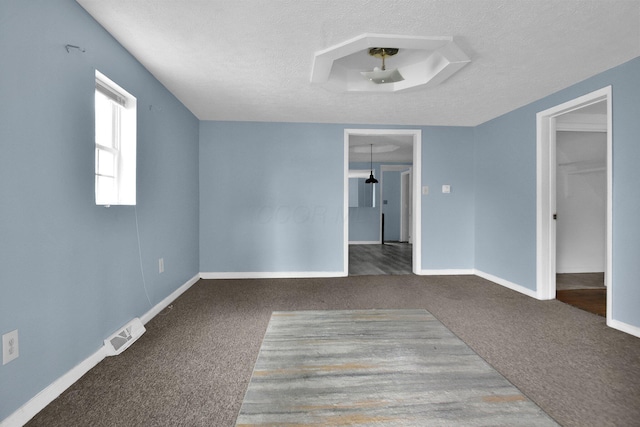 carpeted empty room featuring a textured ceiling