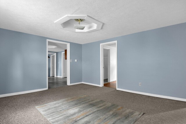 unfurnished room with a textured ceiling and dark carpet