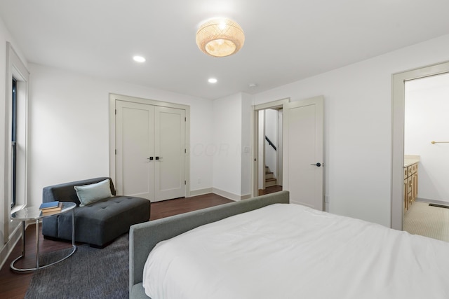 bedroom with ensuite bathroom and dark hardwood / wood-style floors