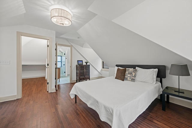 bedroom with a chandelier, dark hardwood / wood-style flooring, lofted ceiling, and a walk in closet