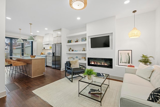 living room with dark hardwood / wood-style floors, built in features, and sink