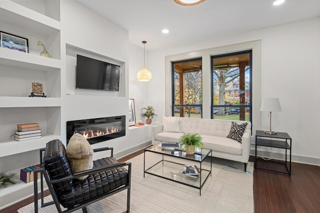 living room featuring built in shelves and hardwood / wood-style floors