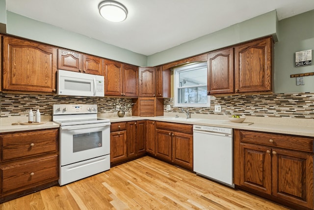 kitchen featuring decorative backsplash, light hardwood / wood-style floors, white appliances, and sink