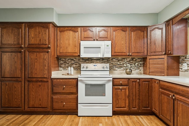 kitchen with light wood-type flooring, white appliances, and backsplash