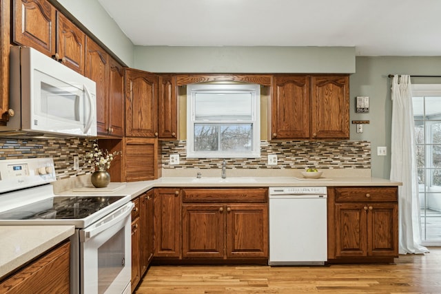 kitchen featuring white appliances, light hardwood / wood-style floors, backsplash, and sink