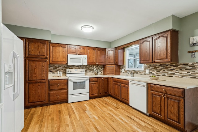 kitchen featuring sink, light wood-type flooring, white appliances, and backsplash