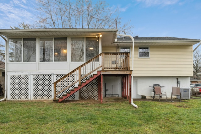 rear view of house with a sunroom, cooling unit, and a lawn