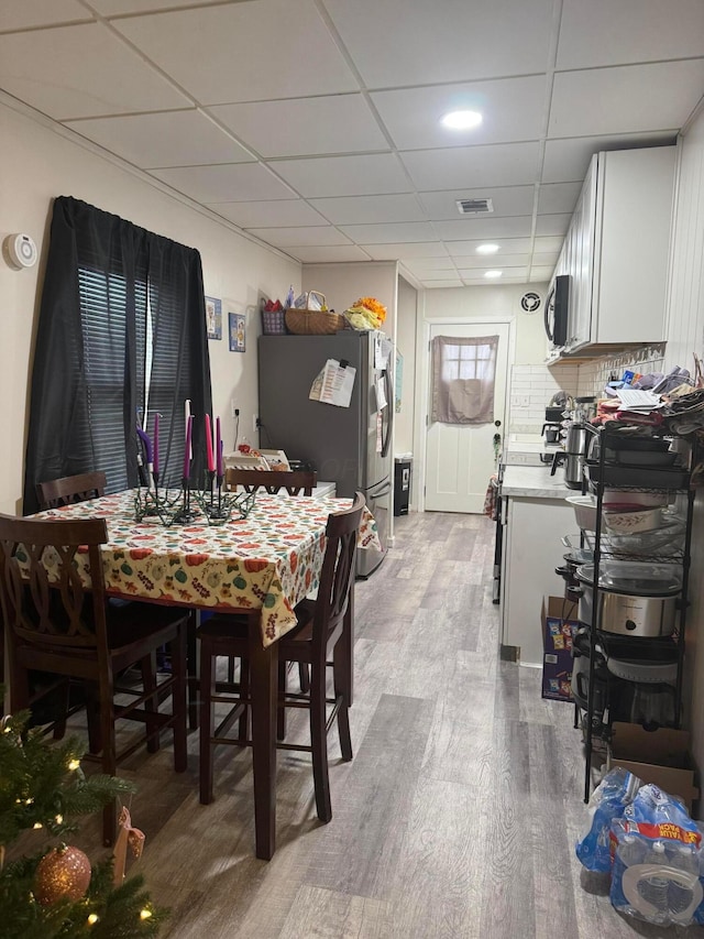 dining area with a drop ceiling and wood-type flooring