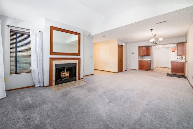 unfurnished living room with a chandelier, light colored carpet, lofted ceiling, and a tiled fireplace