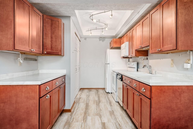 kitchen with sink, rail lighting, a textured ceiling, white appliances, and light wood-type flooring