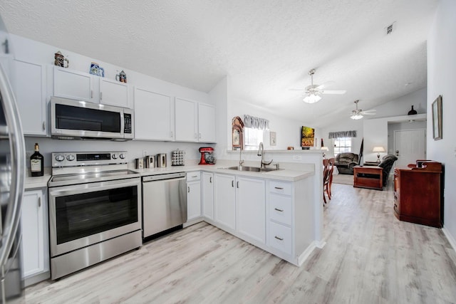 kitchen featuring appliances with stainless steel finishes, sink, white cabinets, kitchen peninsula, and light hardwood / wood-style flooring