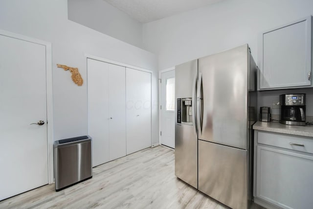 kitchen featuring gray cabinetry, stainless steel fridge, and light wood-type flooring