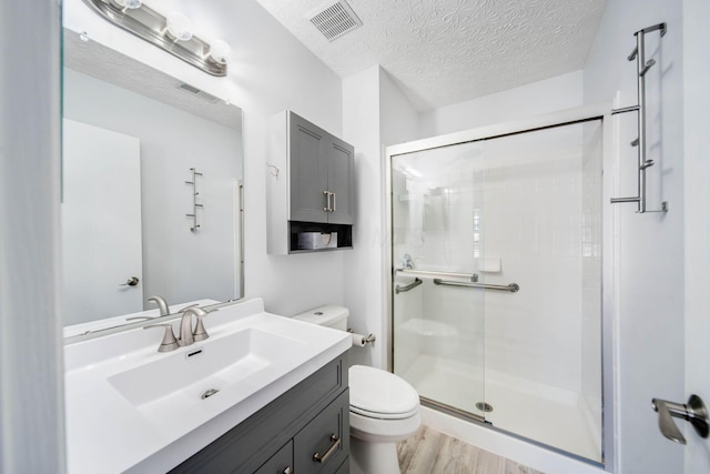 bathroom with walk in shower, toilet, hardwood / wood-style floors, and a textured ceiling