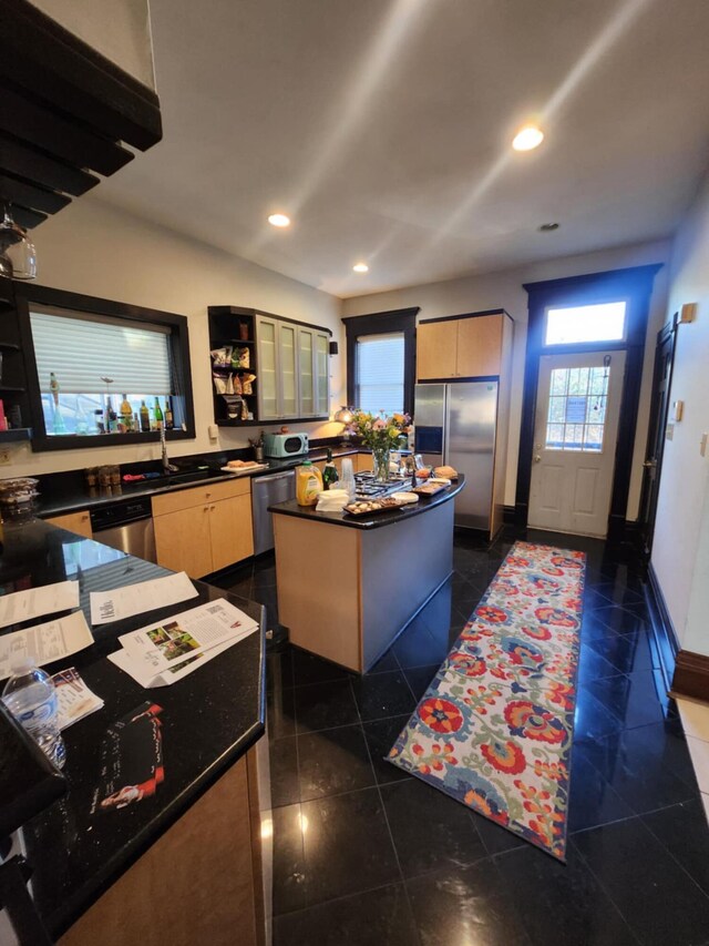 kitchen with dark tile patterned floors, a kitchen island, stainless steel appliances, and light brown cabinets