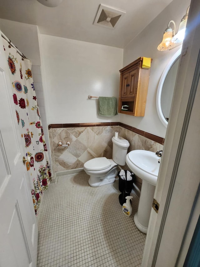 bathroom with tile patterned floors, a shower with curtain, sink, tile walls, and toilet